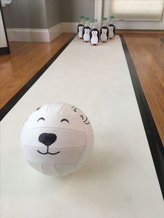 a large white ball sitting on top of a hard wood floor next to penguin bottles