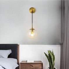 a bedroom with a bed, nightstand and plant on the side table next to it