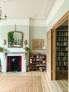 a living room filled with furniture and a fire place in front of a book shelf