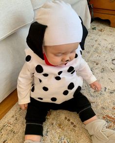 a baby wearing a dalmatian outfit sitting on the floor