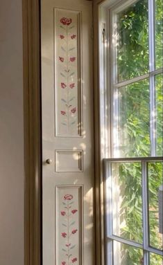 a white door with red flowers painted on it and a window sill in the background