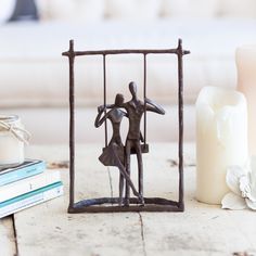 a figurine in a cage next to candles and books on a wooden table