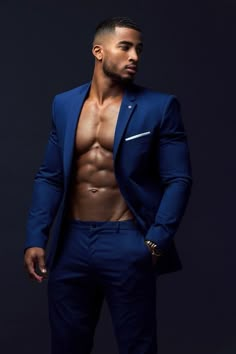 a shirtless man in a blue suit posing for the camera with his hands on his hips