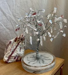 a small tree is sitting on a table next to a rock and glass bead wire