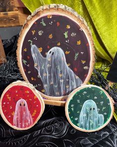 three painted wood slices with ghost images on them