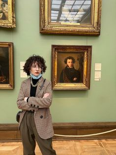 a woman is standing in front of paintings and posing for the camera with her arms crossed