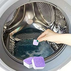 someone is cleaning the front of a washing machine with purple sponges and water in it