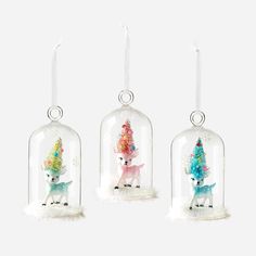 three glass bellow ornaments with small animals in them, one is wearing a unicorn hat and the other has a deer