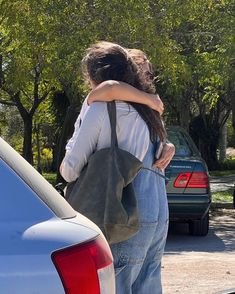 two people hugging each other in front of a car