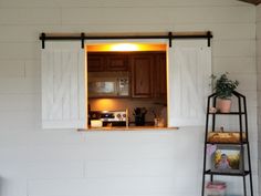 an open window on the side of a white brick wall with a ladder in front of it