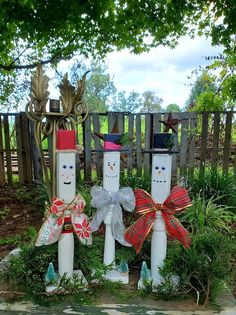 three snowmen made out of toilet paper rolls sitting in the middle of a garden