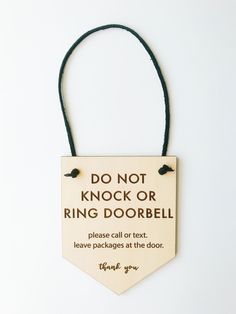 a sign that says do not knock or ring doorbell on a string with a black cord