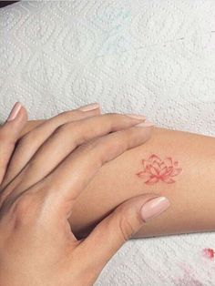 two hands holding each other with a small tattoo on their left arm and the wrist