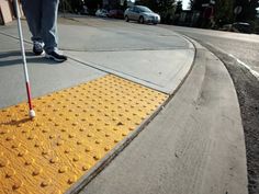 a person with a cane is standing on the sidewalk and has yellow dots painted on it