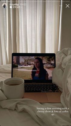 a laptop computer sitting on top of a bed with a cup of coffee in front of it