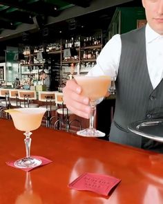 a man in a vest holding a drink at a bar