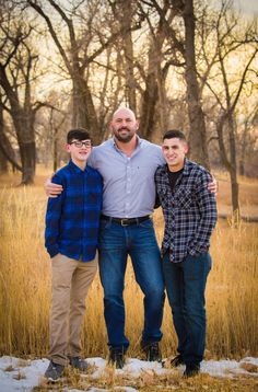 three men standing next to each other in a field