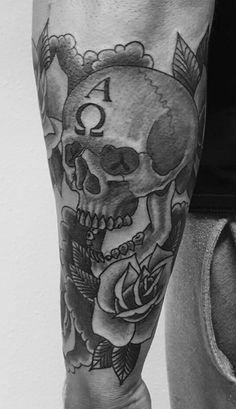 a black and white photo of a man's leg with a skull and roses on it