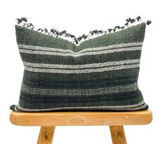 a black and white striped pillow sitting on top of a wooden stool