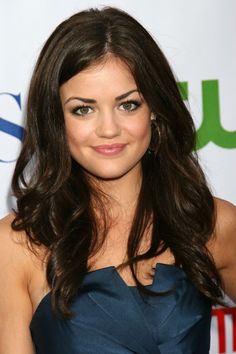 a beautiful young woman with long brown hair wearing a blue dress and smiling at the camera