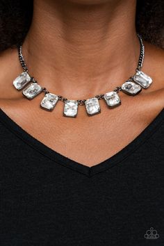 a woman wearing a black shirt and silver necklace with square shaped stones on the front