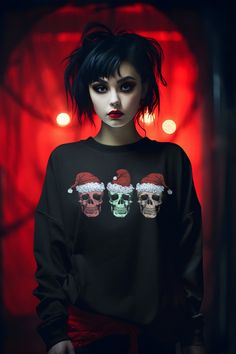 a woman wearing a black sweater with skulls and santa hats on her head, standing in front of red lights