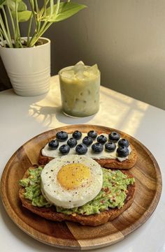 an egg and avocado toast with blueberries is on a plate next to a drink