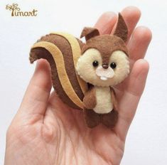 a hand holding a small stuffed animal that looks like a squirrel with a banana on it's tail