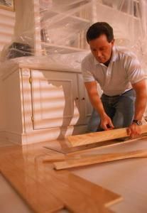 a man kneeling on the floor working on some wood