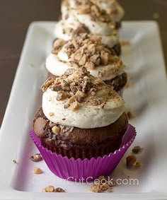 some cupcakes with white frosting and chocolate sprinkles on a plate