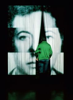 a man standing in front of a large screen with a woman's face on it