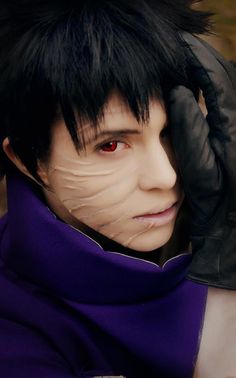 a man with black hair and red eyes wearing gloves