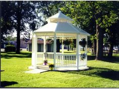 a white gazebo sitting on top of a lush green field