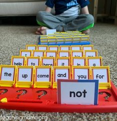 a young boy sitting on the floor next to a pile of cards with words in them