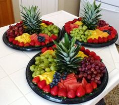 three plates filled with fruit on top of a white kitchen counter next to a refrigerator