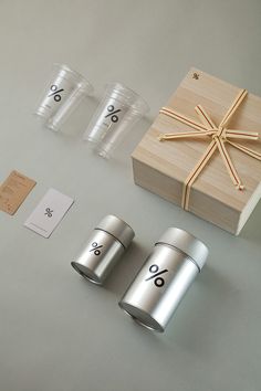 two silver cups sitting on top of a table next to a wooden box and tags