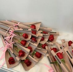 a bunch of roses are wrapped in brown paper and tied with pink ribbon on a table