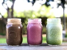 three jars filled with different colored liquid sitting on top of a wooden table