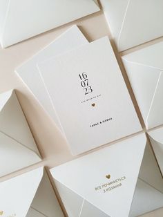 the wedding stationery is laid out on top of white envelopes with gold foil