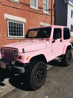 a pink jeep parked in front of a brick building