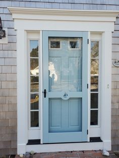 a blue front door with two windows and a brick walkway leading up to the house