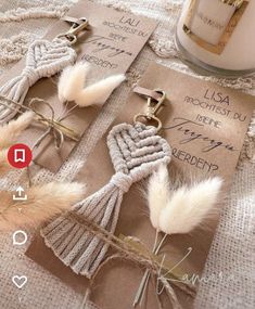 two key chains with feathers attached to them sitting on a table next to a candle