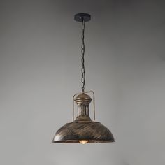 an old fashioned pendant light hanging from a chain on a gray wall in a kitchen