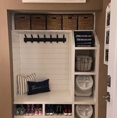 an organized mud room with white shelves and baskets