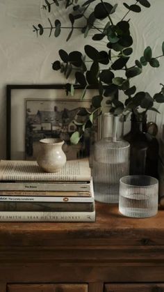 some books and vases are sitting on a dresser