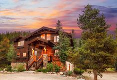 a log cabin sits in the woods at sunset