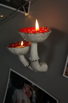 two red candles are lit in the middle of a white candle holder on a wall