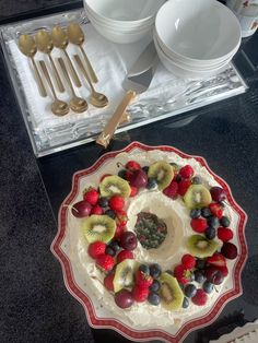 there is a cake with fruit on it and gold spoons next to the plate