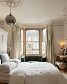 a bedroom with a bed, chair and large window in it's center area