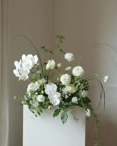 a white vase with flowers and greenery in it